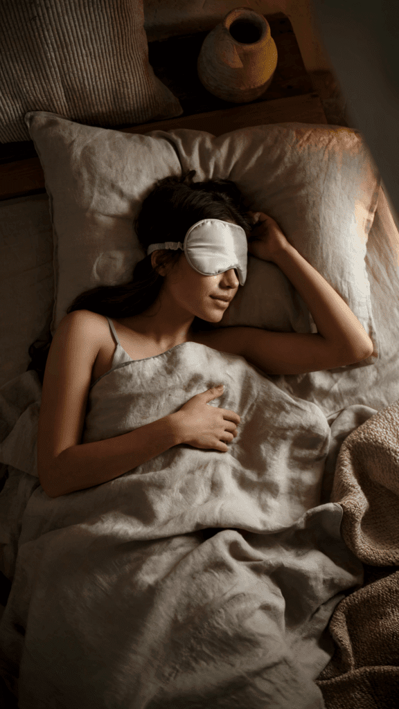 a woman sleeping in bed with an eye mask on